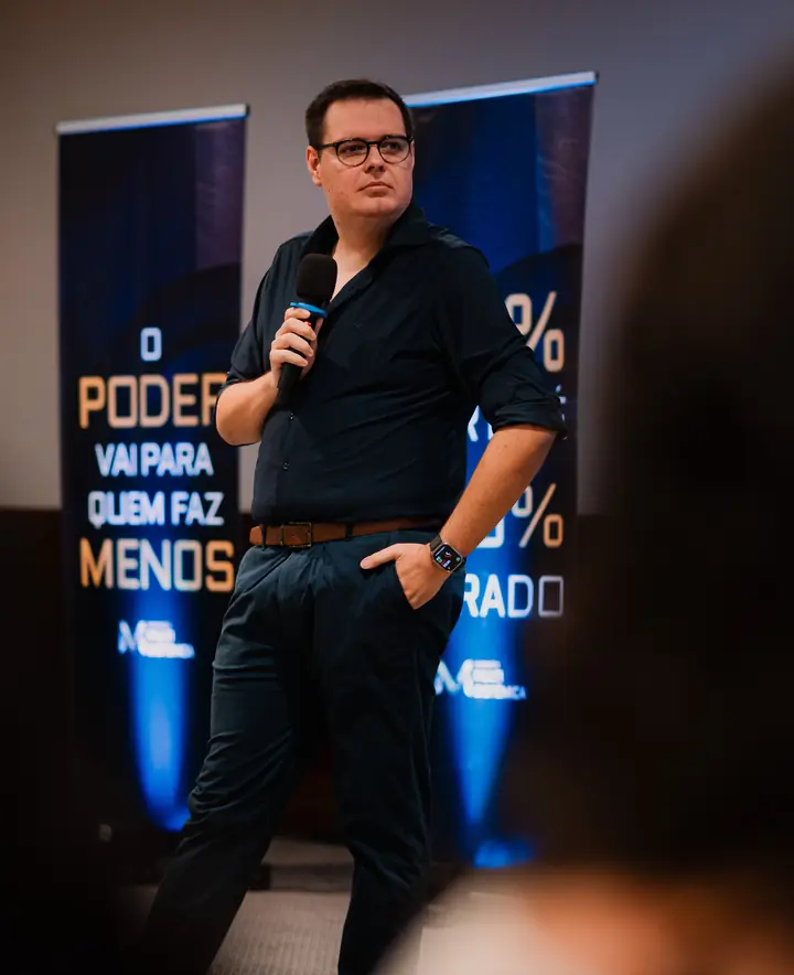 Marcos Duda em pé no palco, com microfone na mão